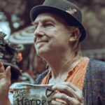 Man in vintage attire holding a sign at a Renaissance fair.